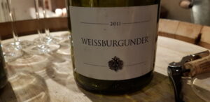 Weißburgunder Flasche und Weingläser auf Holztisch.