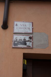 Straßenschild "Via Cavour" mit historischem Foto.