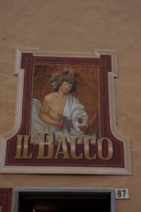 Schild "Il Bacco" mit Wein und Trauben.