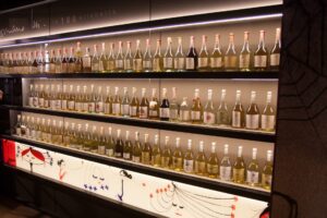 Weinflaschen auf beleuchtetem Regal in Vinothek