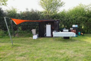 Gartenhütte mit Campingausrüstung und Tisch.