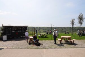 Foodtruck und Gäste im Freien mit Hügelblick.