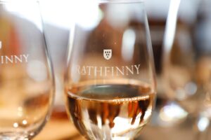 Weingläser mit Logo "Rathfinny" und Weißwein.
