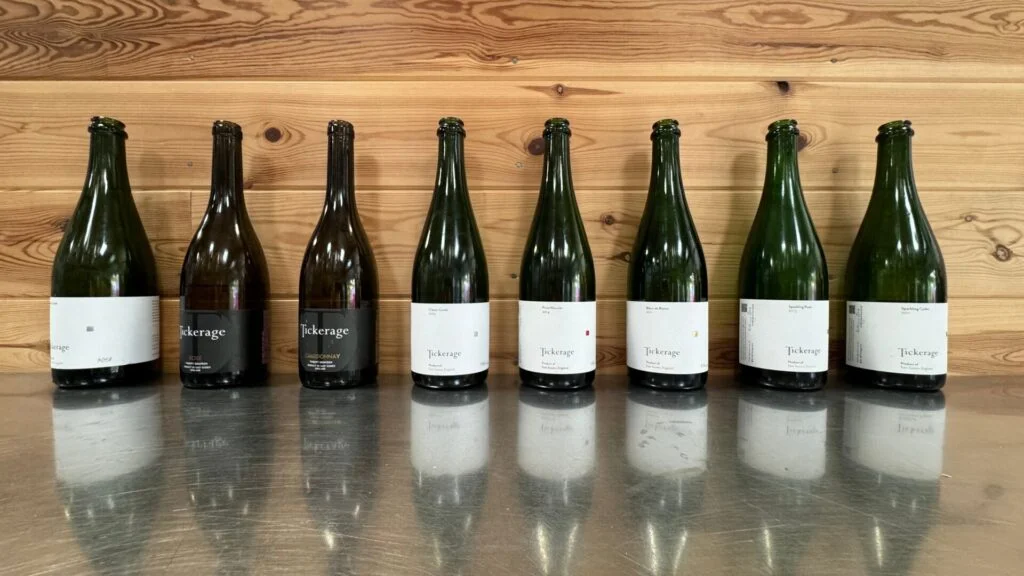 Reihe von Weißweinflaschen auf Holzhintergrund.