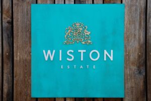 Türkisschild mit Wiston Estate Logo und Schriftzug.